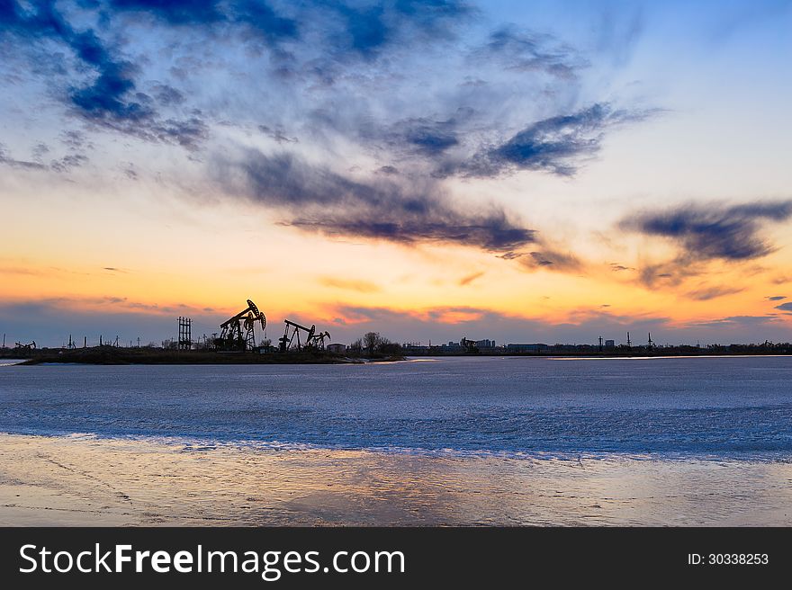 China's heilongjiang Province, Daqing City,Sunset glow of snow and ice was meltting lake.The oil pumping machine on ice lake.