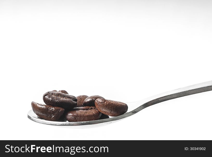 Coffee beans on a spoon isolated on white