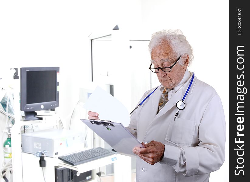 Senior doctor looking at a paper on a clipboard with a pulmonary function lab blurred in the back ground. Senior doctor looking at a paper on a clipboard with a pulmonary function lab blurred in the back ground.