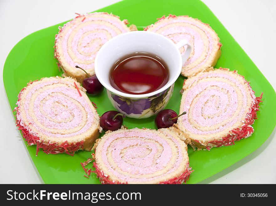 Sliced â€‹â€‹cherry strudel on a green plate with a cup of tea