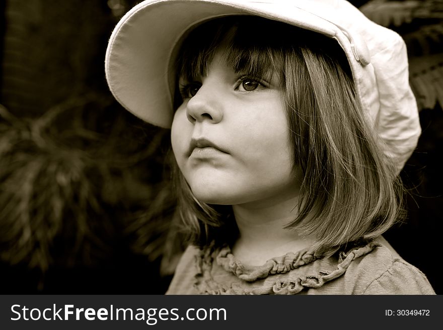 Monochrome portrait of a little girl with the big cap on her head with serious expression. Monochrome portrait of a little girl with the big cap on her head with serious expression