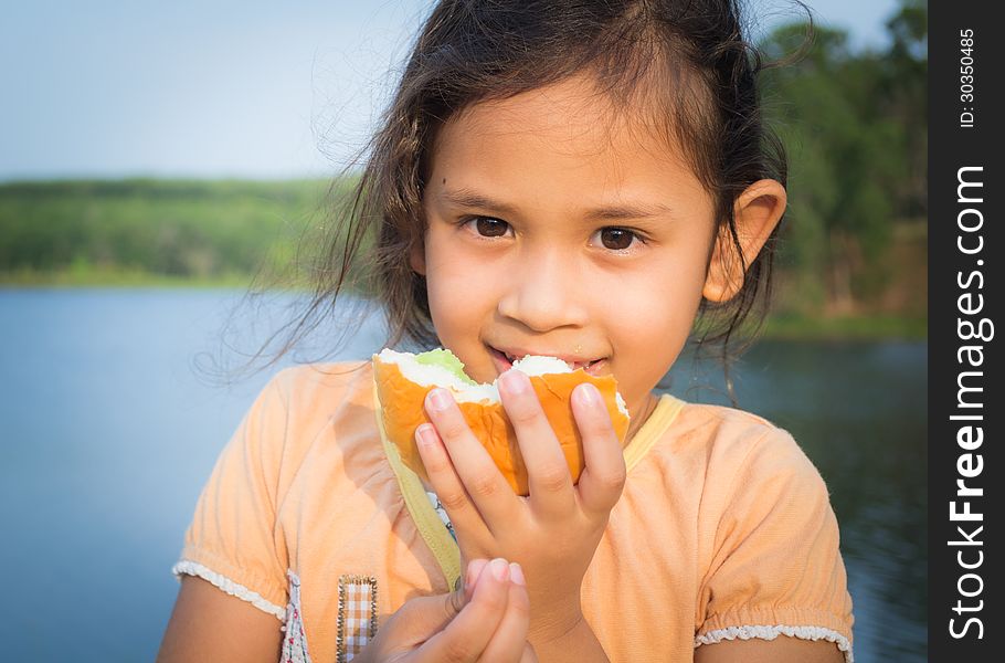 A cute girl eatting a bread in the park