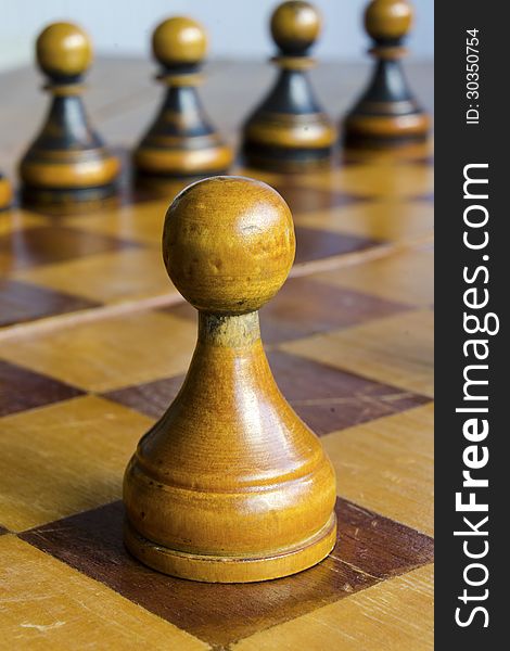 Vintage white pawn piece on wooden chessboard