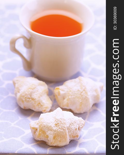 Shortbread cookies covered with powdered sugar and a cup of tea. Shortbread cookies covered with powdered sugar and a cup of tea