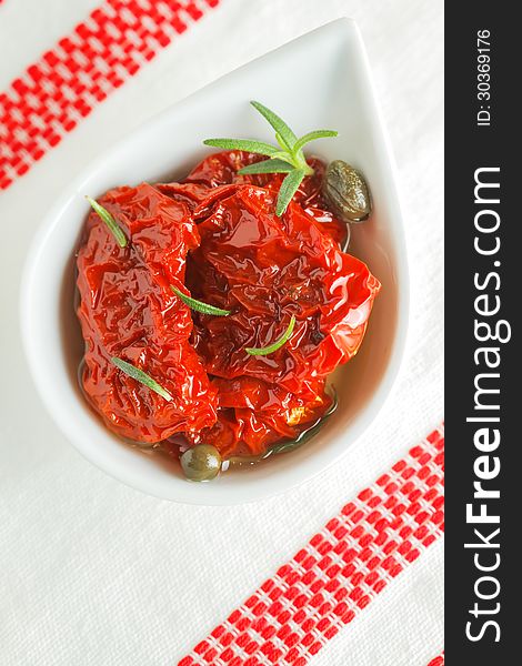 Dried tomatoes in olive oil with capers and rosemary