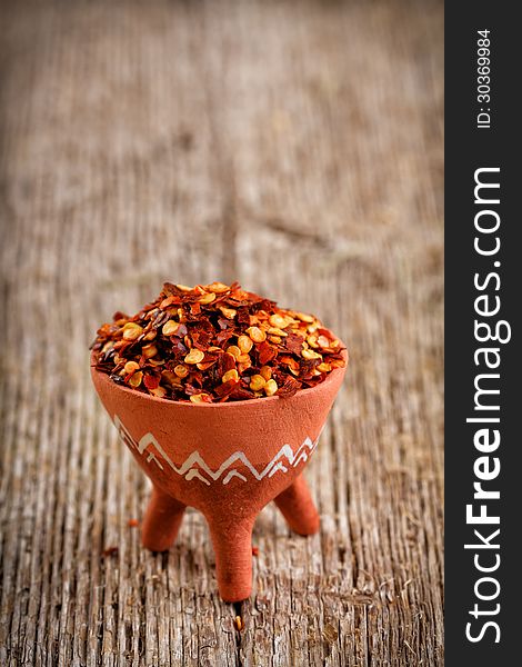 Dried red pepper flakes on rustic wooden plank