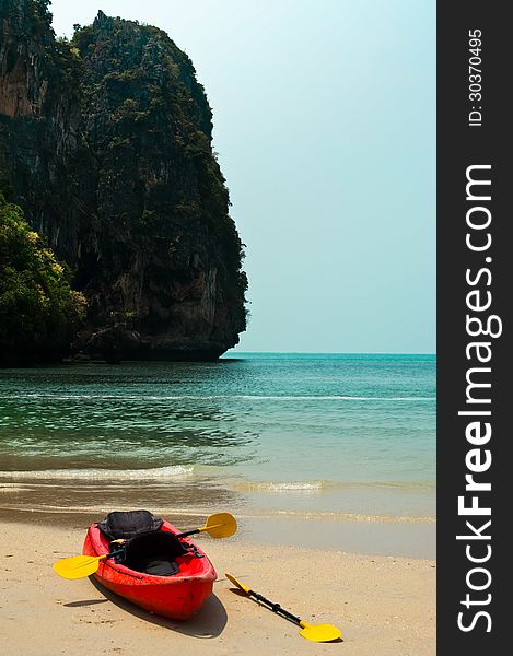 Tropical beach landscape with red canoe boat at ocean gulf under blue sky. Pranang cave beach, Railay, Krabi, Thailand