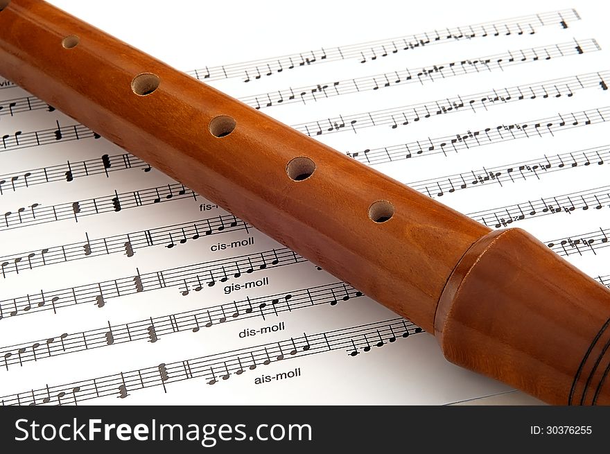 Wooden flute lying on musical notation. Wooden flute lying on musical notation