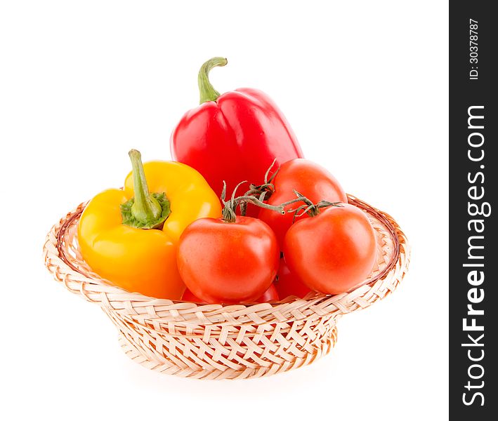 Tomatoes and peppers in a wicker basket on a white background