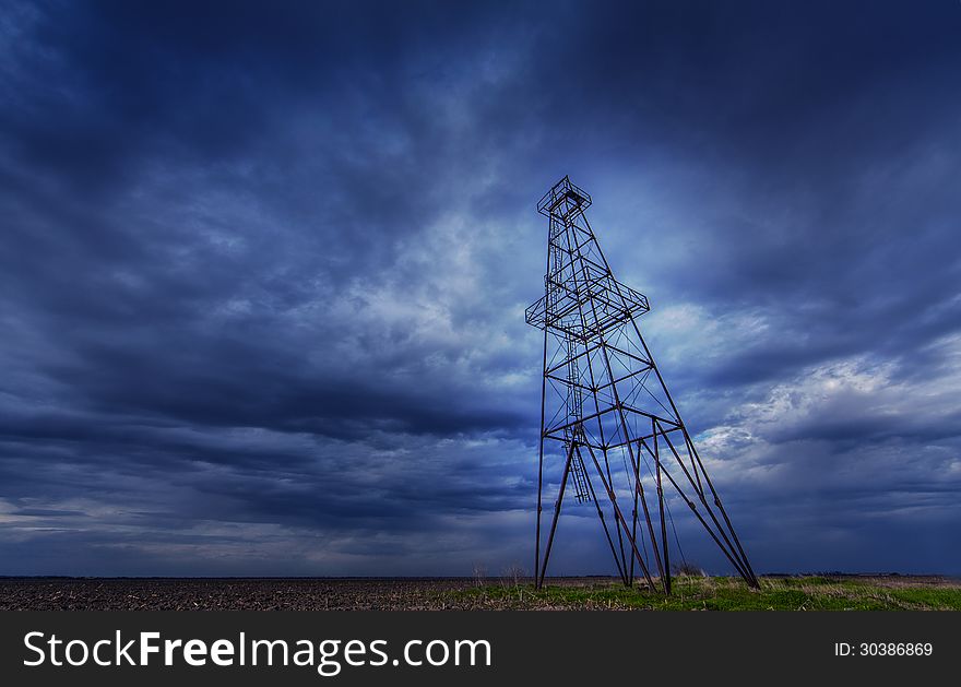 Oil and gas rig structure profiled on ominous stormy sky in active oilfield in Europe. Oil and gas rig structure profiled on ominous stormy sky in active oilfield in Europe