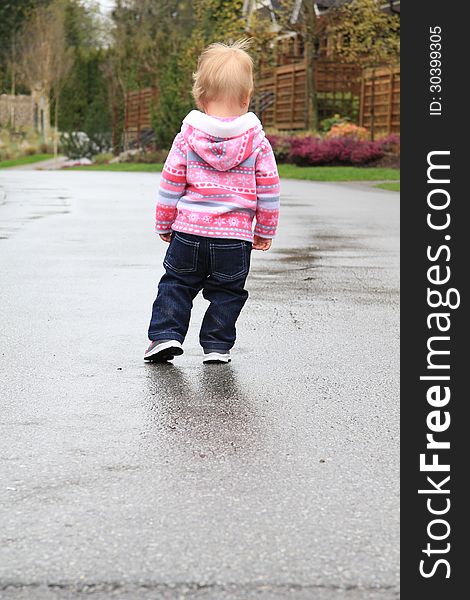 One year old little girl playing in a water puddle. One year old little girl playing in a water puddle.