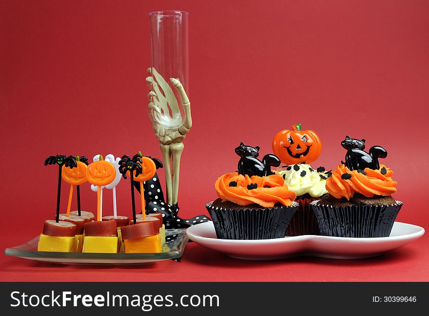 Happy Halloween party food with skeleton hand glass on red background.