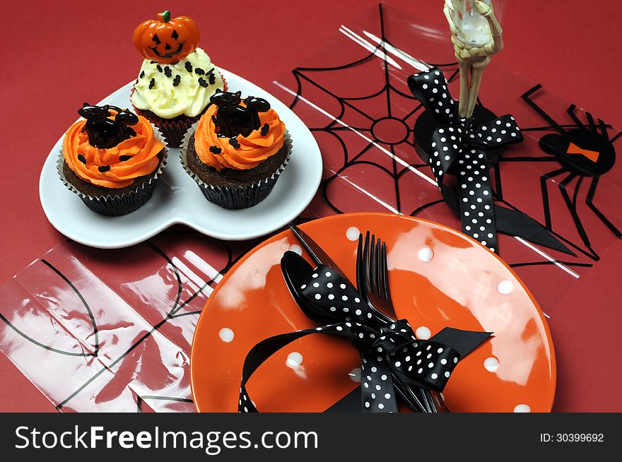 Happy Halloween party table with orange polka dot plate and chocolate cupcakes with black cat and pumpkin decorations. Happy Halloween party table with orange polka dot plate and chocolate cupcakes with black cat and pumpkin decorations.