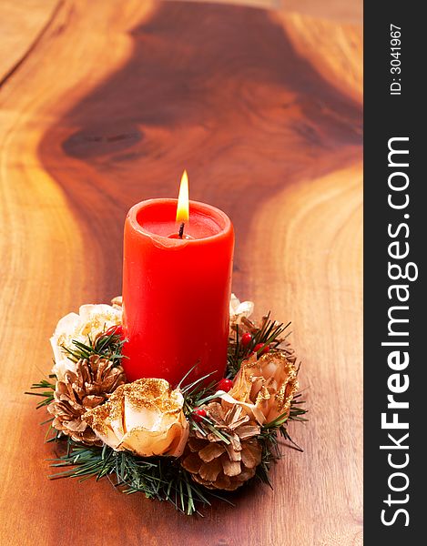 Single red candle in a Christmas decoration on wooden table