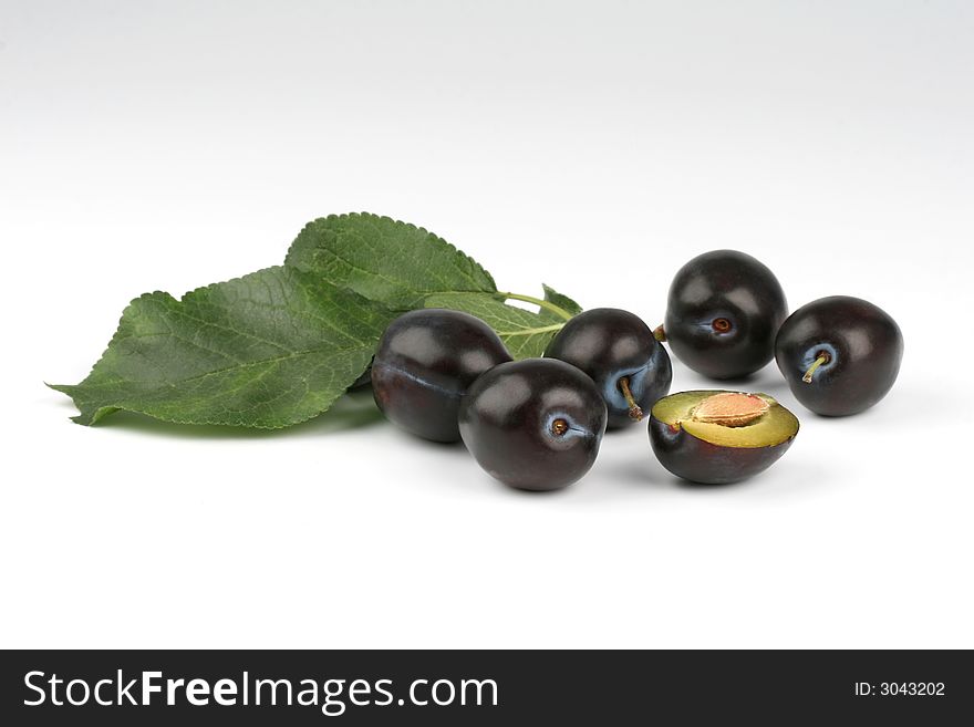 Plumbs with leaves on the white background