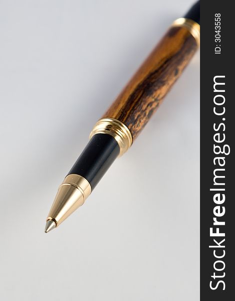A handmade roller ball pen isolated on white with a shallow depth of field (dof).  The pen is made from Bocote wood with a walnut segment.  (The pen was handmade by the photographer in his studio). A handmade roller ball pen isolated on white with a shallow depth of field (dof).  The pen is made from Bocote wood with a walnut segment.  (The pen was handmade by the photographer in his studio).