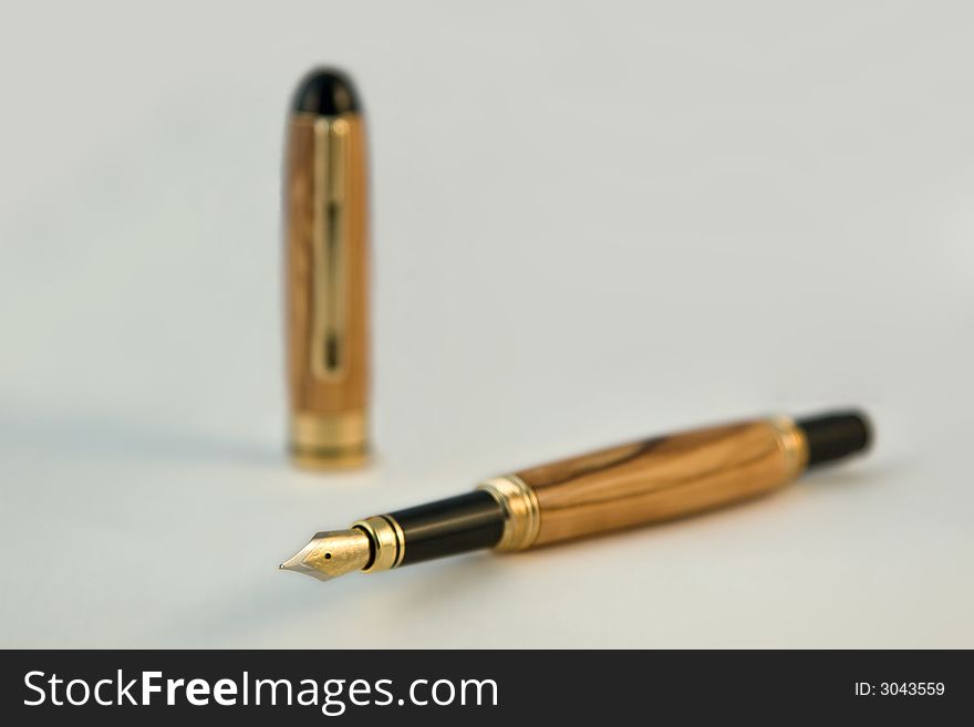 A handmade fountain pen displayed on white with a shallow depth of field (dof). The pen is made from Bethlehem Olive Wood. (The pen was handmade by the photographer in his studio). A handmade fountain pen displayed on white with a shallow depth of field (dof). The pen is made from Bethlehem Olive Wood. (The pen was handmade by the photographer in his studio).