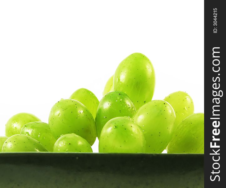 Wet grapes fruits in bowl on white background