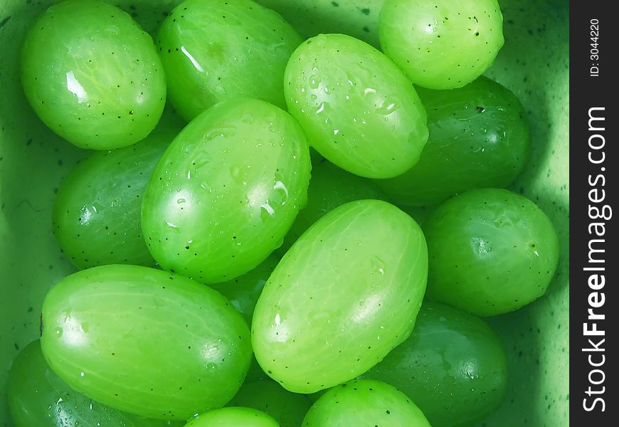 Wet grapes fruits in green bowl