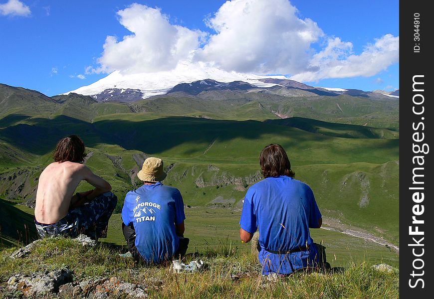 Three man are looking at Elbrus mountain. Three man are looking at Elbrus mountain