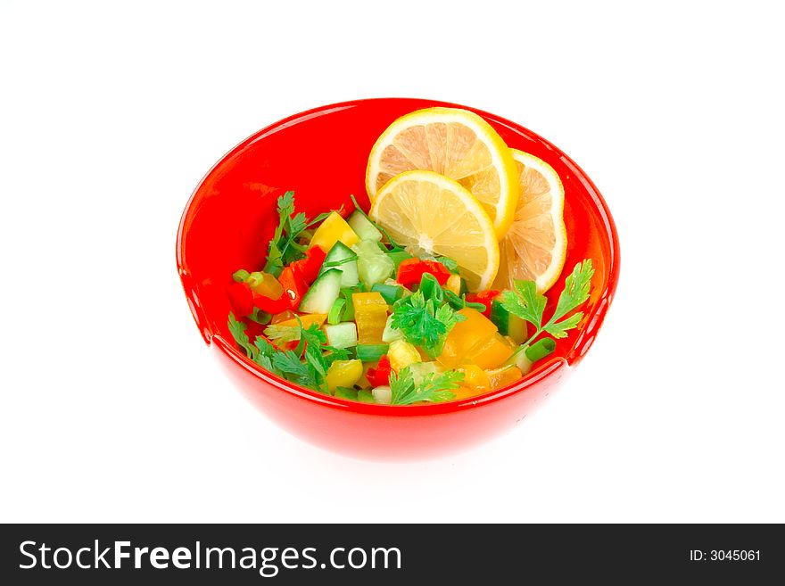 Bright red bowl of freshly chopped green healthy salad with three lemon slices isolated on thire. Bright red bowl of freshly chopped green healthy salad with three lemon slices isolated on thire
