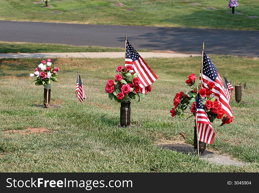 Flowers and American flags along grave sites at a cemetery. Flowers and American flags along grave sites at a cemetery