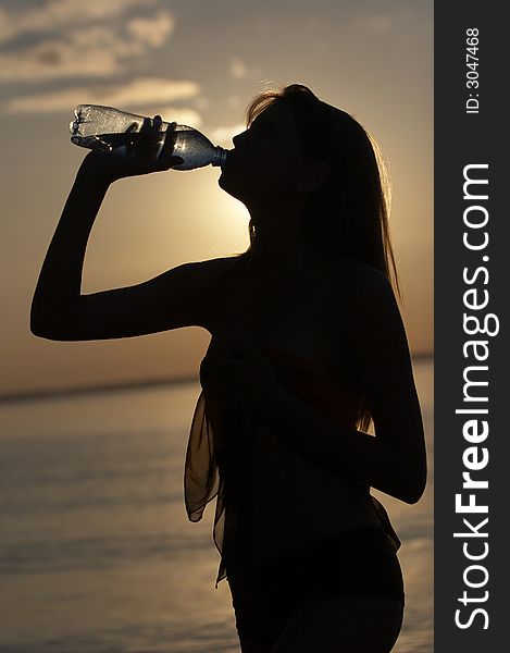 Silhouette of girl drink water on water/sky background. Silhouette of girl drink water on water/sky background