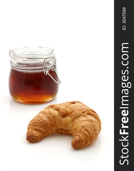 Honey and croissant isolated on white