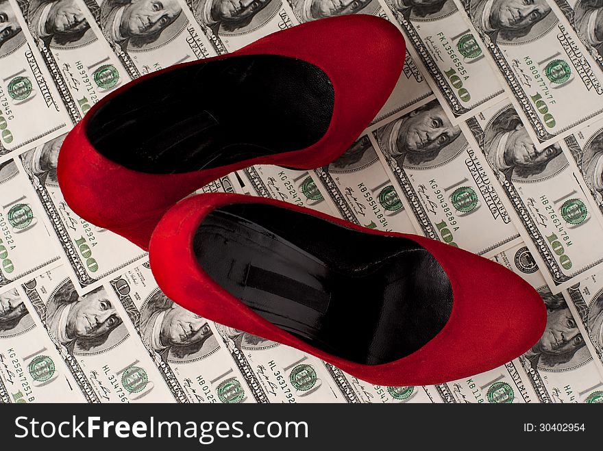 Pair of red female shoes and dollars on black background. Studio shot. Pair of red female shoes and dollars on black background. Studio shot.