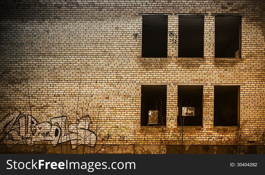 Neglected brick wall building without windowpanes and covered with graffiti. Neglected brick wall building without windowpanes and covered with graffiti.