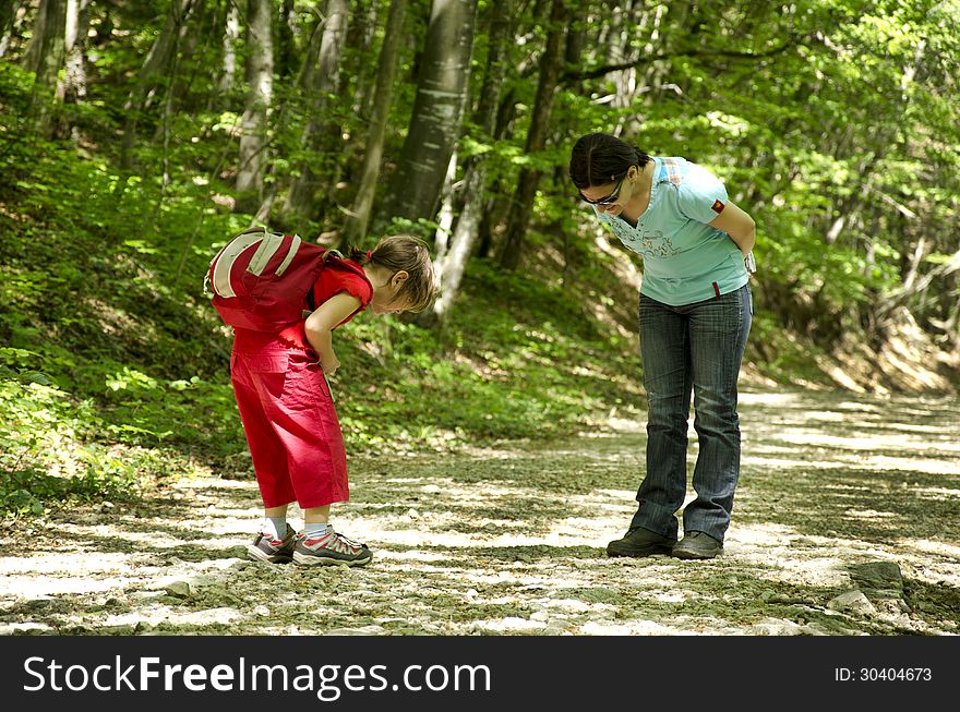 Mother and daughter looking for something in the forest. Mother and daughter looking for something in the forest