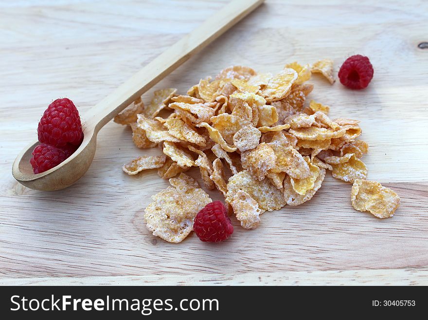 Fresh respberries and frosted cereal with wooden spoon on cutting board. Fresh respberries and frosted cereal with wooden spoon on cutting board.