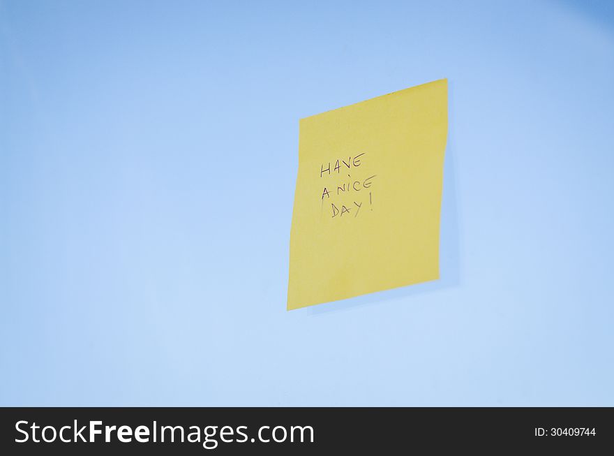 Have a nice day text handwritten on a sticky note against blue background with shadow