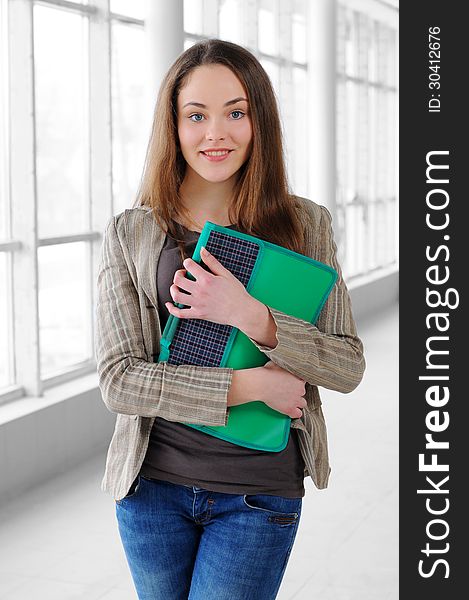 Young business girl with a folder in hands at office