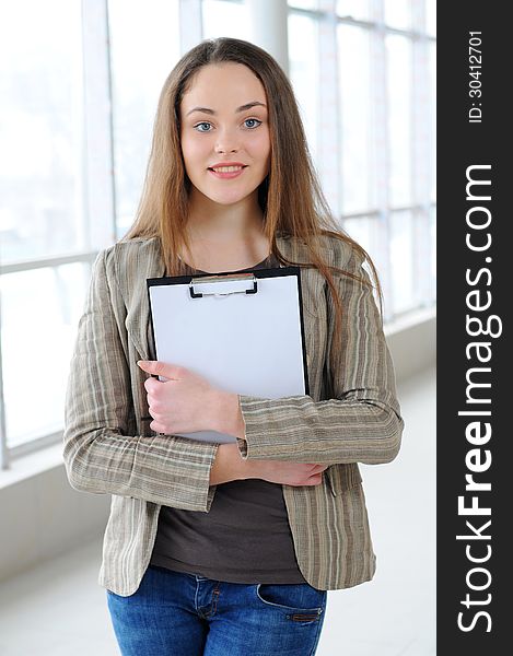 Young business girl with a folder in hands at office