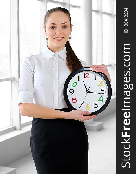 Portrait of a young business girl with a clock in the office