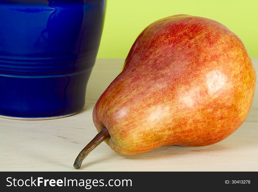 Pear and blue pitcher on a yellow background. Pear and blue pitcher on a yellow background