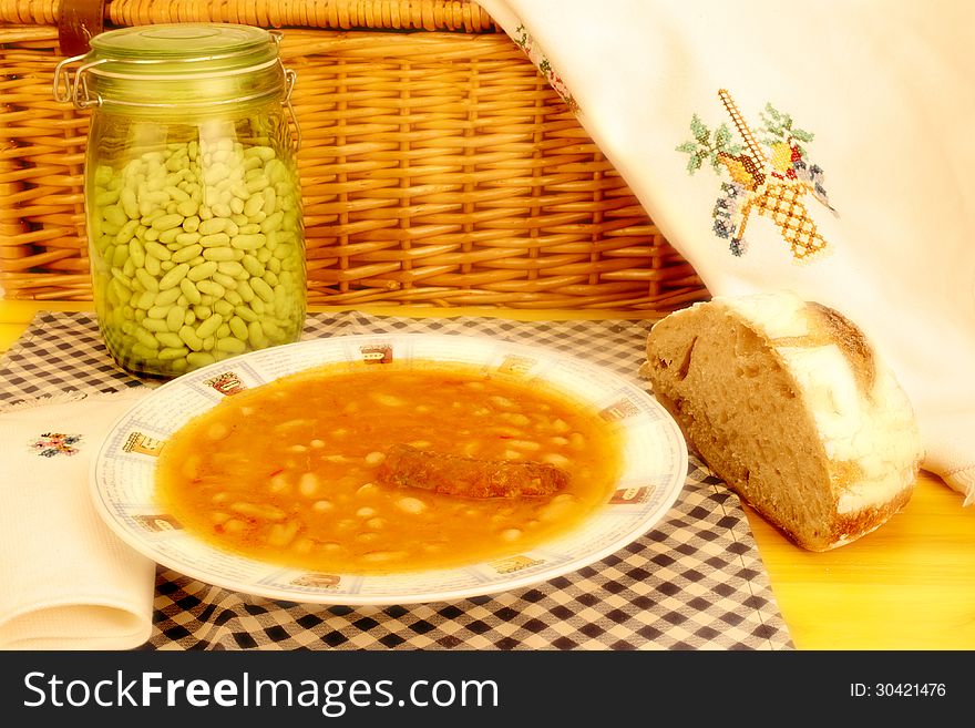 Plate of beans with chorizo, Spanish traditional and homemade bread on wooden table. Plate of beans with chorizo, Spanish traditional and homemade bread on wooden table