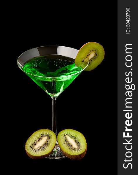 Glass filed with green beverage and a pieces of kiwi. Black background. Studio shot.