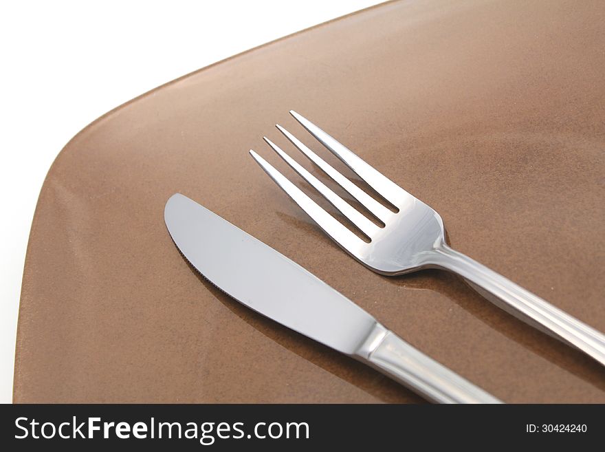 Knife and fork on brown plastic plate over white