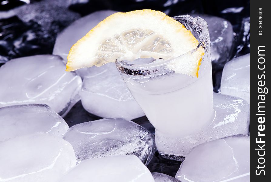 Vodka with lemon poured in a glass made of ice. Vodka with lemon poured in a glass made of ice