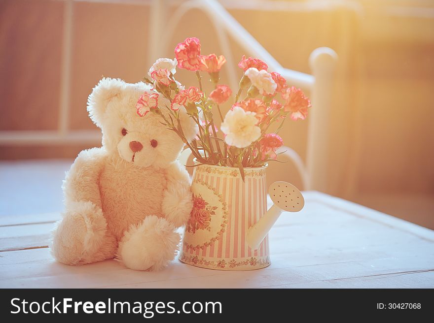 Still life with teddy bear and pink flowers in the watering can with soft back light. Still life with teddy bear and pink flowers in the watering can with soft back light