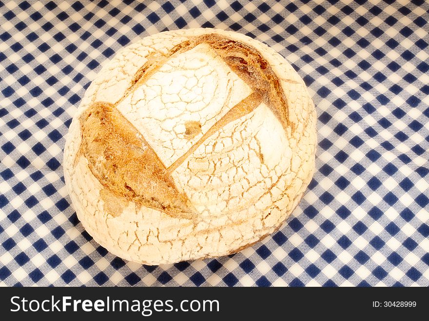 Rustic organic bread made ??by hand on a blue checkered tablecloth
