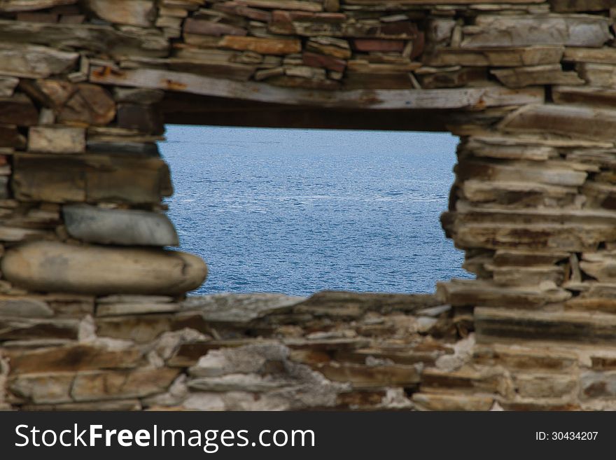 Window from blue sea stone wall blurred ruined house. Window from blue sea stone wall blurred ruined house