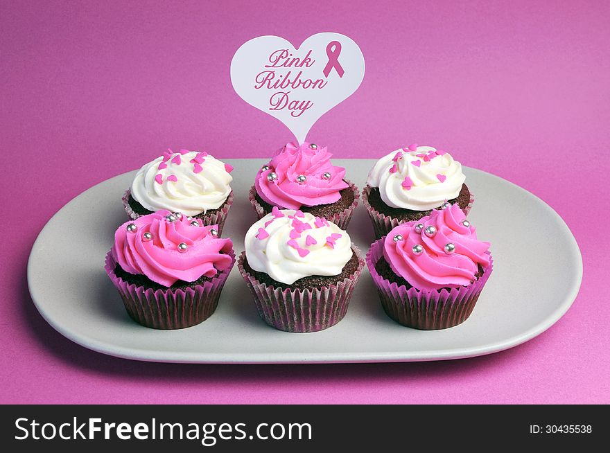 Pink Ribbon Day message across white heart toppers on pink and white decorated red velvet cupcakes