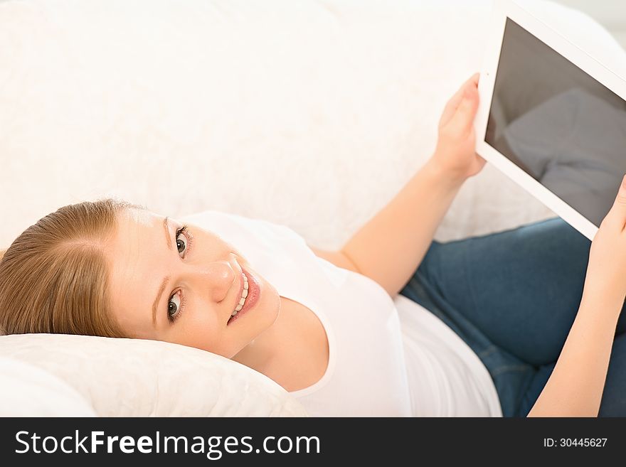 Young beautiful woman relaxing at home with a Tablet PC