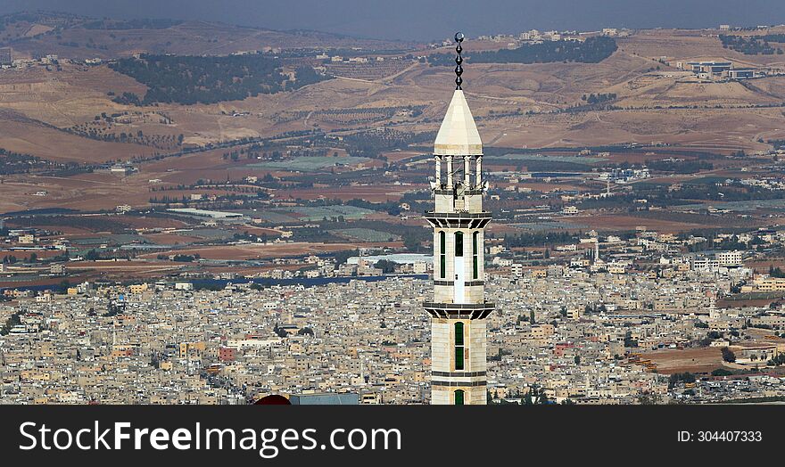 The minaret of a mosque behind it is a crowded low-lying residential area