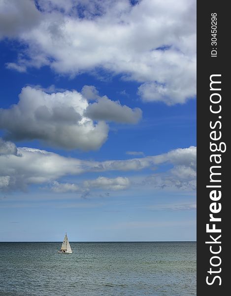 A lonely sail boat out in the ocean.