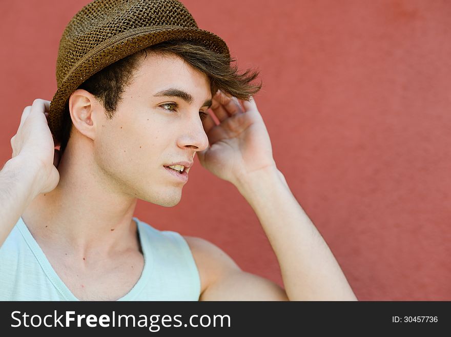 Portrait of attractive young man in urban background wearing a sun hat