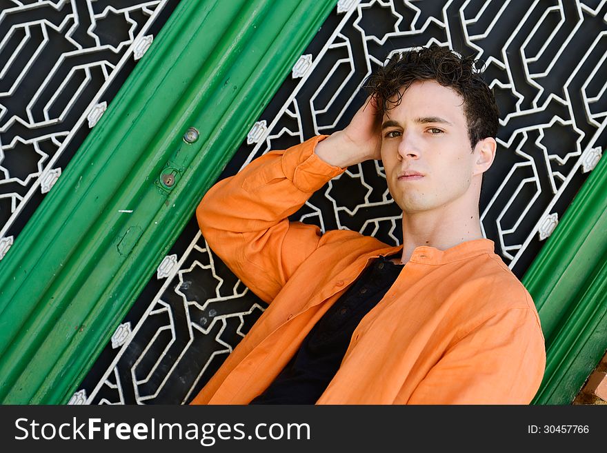 Portrait of attractive young man in urban background wearing orange shirt